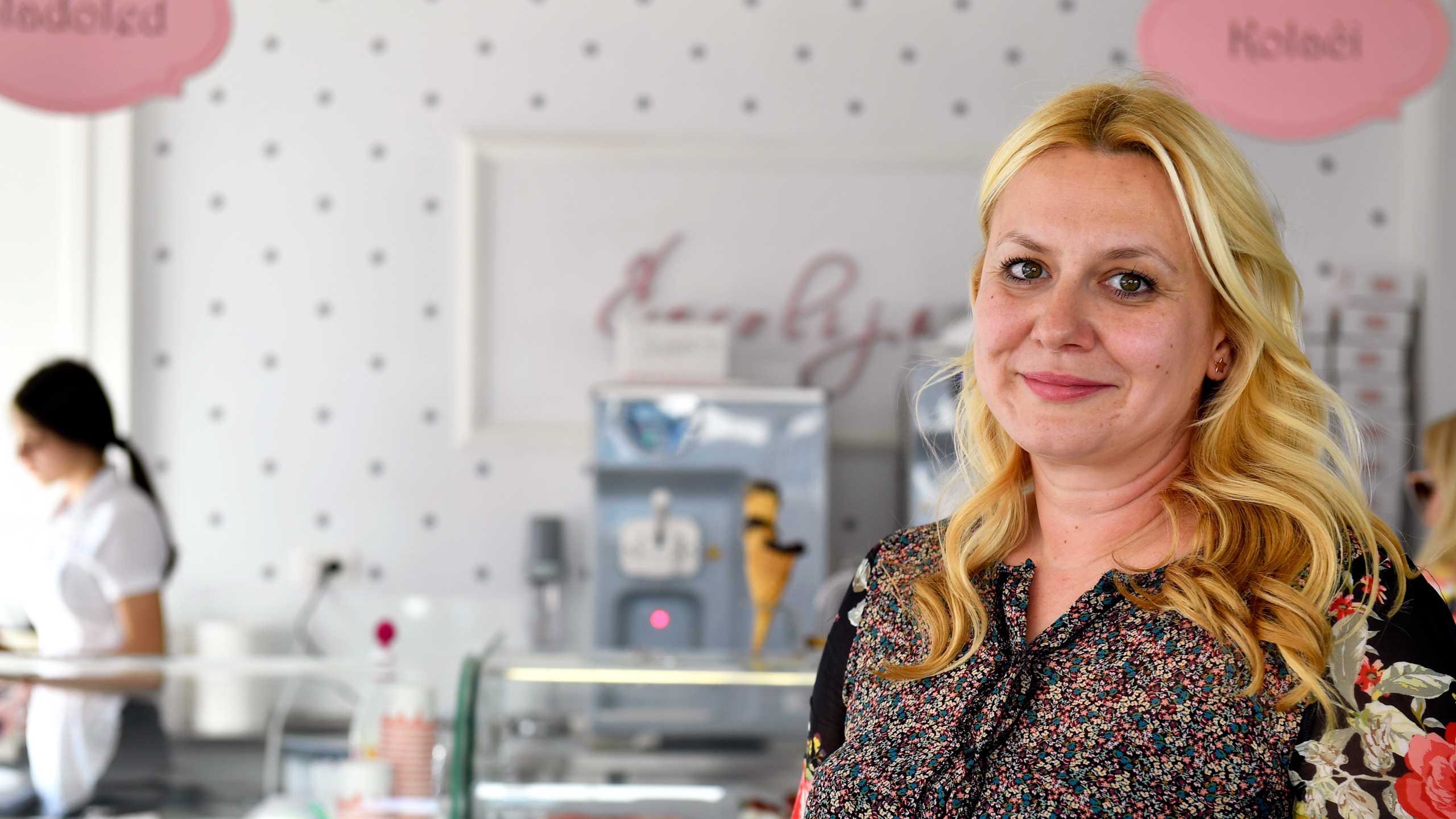 Portrait of Ivana Jovovic, owner of Cafe Carolija, smiling at the camera with Cafe Carolija in the background