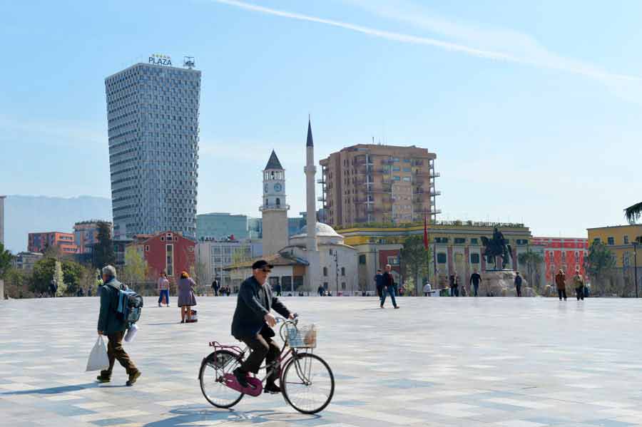 A mna cycles his bicycle across a square in Tirana, Albania