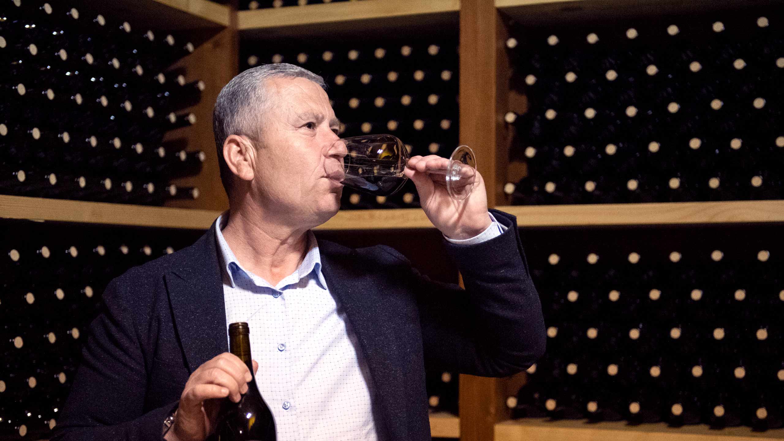 Mr Gjini drinking a glass of his wine in the Kallmetti wine cellar